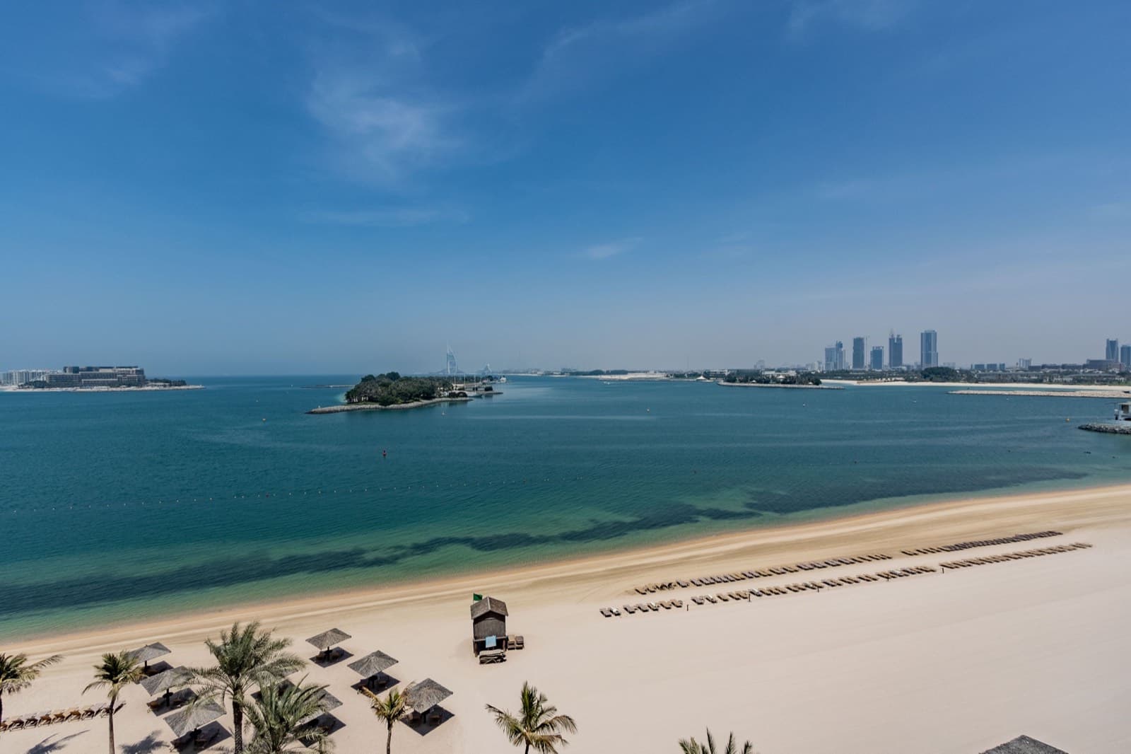 Soukromá hotelová pláž s palmami a lehátky u Perského zálivu - typické zázemí all inclusive resortu v Dubaji