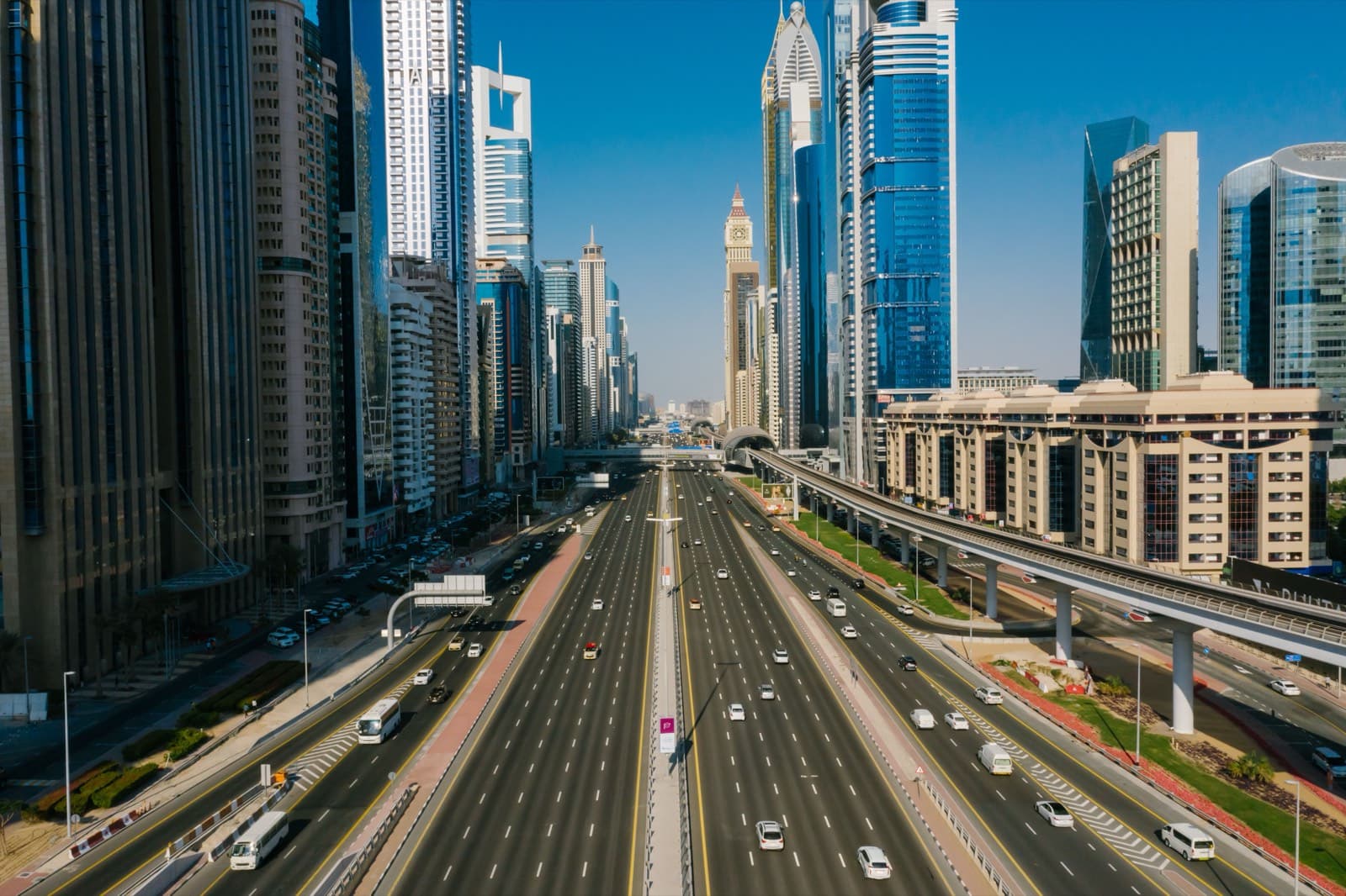 Dálnice Sheikh Zayed Road v Dubaji s mnoha jízdními pruhy, mrakodrapy po obou stranách a trasou metra